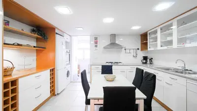 a kitchen with white cabinets and a table and chairs at Bed&BCN Gracia III in Barcelona