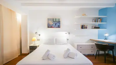 a bedroom with a white bed with a desk and a chair at Bed&BCN Gracia III in Barcelona