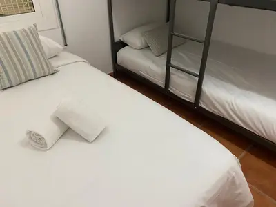 two beds with white sheets and a shelf at Vilamarlux V in Vilassar de Mar