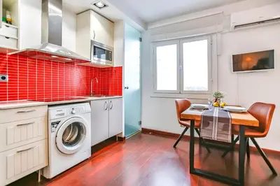 a kitchen with a washing machine and a table with chairs at Ghat Apartments Montroig in Sitges