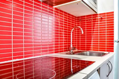 a kitchen with red tiled walls and a sink at Ghat Apartments Montroig in Sitges