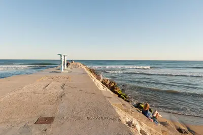 a group of people sitting on the beach near the ocean at Ghat Apartments Montroig in Sitges