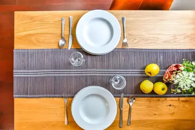 a table with plates and silverware on a wooden table at Ghat Apartments Montroig in Sitges