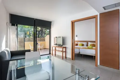 a living room with a couch and a television at Aparthotel Las Palmeras Castelldefels in Castelldefels