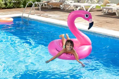 a little girl in a pink flamingo in a pool at Aparthotel Las Palmeras Castelldefels in Castelldefels