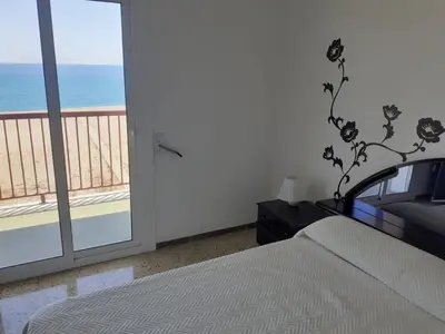 a bedroom with a bed and a view of the ocean at Suitur apartamento primera linea mar vistas playa in Canet de Mar