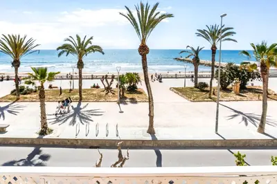 a view of the beach and palm trees at Apart Cozy On The Front Line, Liliane in Sitges