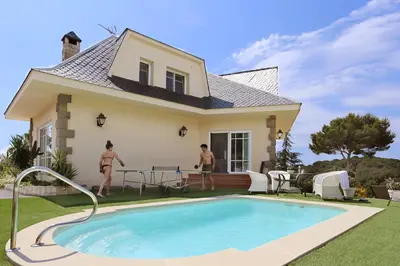two people in front of a house with a swimming pool at Homestay Villa Estrella - Costa Brava in Calella