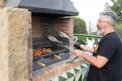 a man is cooking food in a brick oven at Homestay Villa Estrella - Costa Brava in Calella