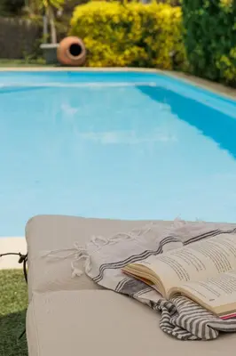 a book sitting on a bench next to a swimming pool at CIM Apartments in Olivella