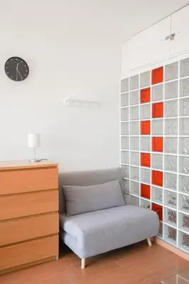 a room with a couch and a clock on a wall at Loft Ponent, Sant Pol de Mar in San Pol de Mar
