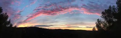 a sunset in the sky with trees in the foreground at TERRAVU in Sant Pere de Ribes
