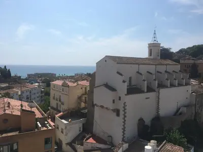 a white building with a tower on top of it at Beautiful apartment 5 minutes walk to the beach in Caldes d'Estrac