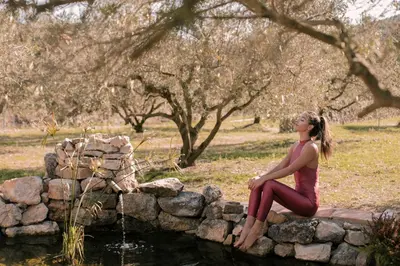 a woman sitting on a rock wall by a pond at Suite con Burbuja in Canyelles
