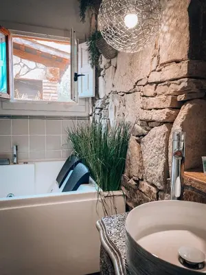 a bathroom with a stone wall and a tub and a sink at Suite con Burbuja in Canyelles