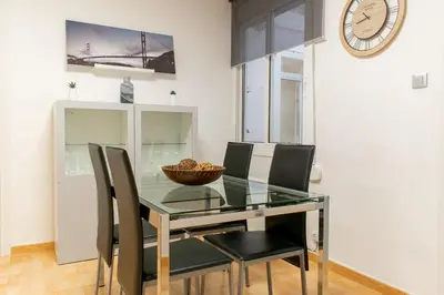 a dining room with a glass table and chairs and a clock at Ahllenrock Cornellà - Parking Gratis- Cerca BCN in Cornellà de Llobregat