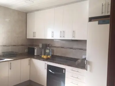a kitchen with white cabinets and a black dishwasher at Casa Feliz in Sant Cebrià de Vallalta