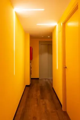 an empty hallway with yellow walls and wooden floors at Hostelle - Women only hostel Barcelona in Barcelona