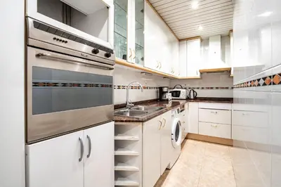 a kitchen with white cabinets and a sink at Stay U-nique Apartments Marina in Barcelona