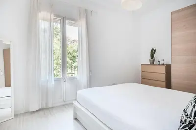 a white bedroom with a bed and a window at Spacious 3 bed Apt in the heart of Sant Antoni, Barcelona in Barcelona