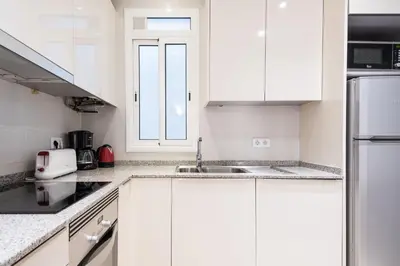 a white kitchen with white cabinets and a sink at Spacious 3 bed Apt in the heart of Sant Antoni, Barcelona in Barcelona