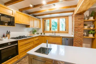 a kitchen with wooden cabinets and a white counter top at Villa Can Duarry - Barcelona Country House 1 in Premia de Dalt