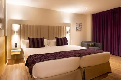 a hotel room with a large bed and purple curtains at Hotel Sansi Barcelona in Barcelona