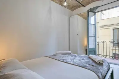 a white bedroom with a bed and a window at Apartamento Alejandro en BCN in Barcelona