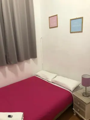 a small bedroom with a bed with a purple blanket at Hostal MiMi Las Ramblas in Barcelona