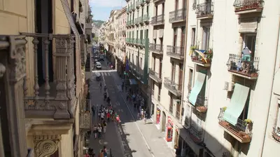 a group of people walking down a street between buildings at Hostal MiMi Las Ramblas in Barcelona