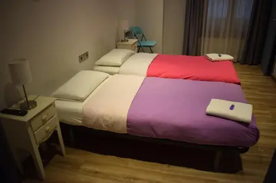 a bedroom with two beds with colorful sheets and a night stand at Hostal MiMi Las Ramblas in Barcelona