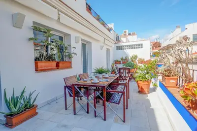 a patio with tables and chairs and potted plants at Angel Views Penthouse by Hello Homes Sitges in Sitges