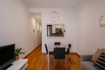 a living room with a table and chairs and a clock at Cute Apartment in Barcelona