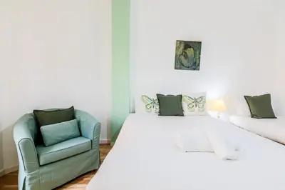 a bedroom with a white bed and a chair at Be barcelona arco del triunfo sunny colors III in Barcelona