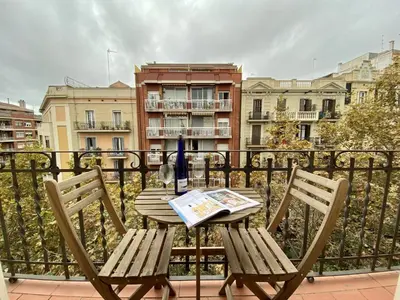 a table and chairs on a balcony with a newspaper at Sagrada familia apartment in Barcelona