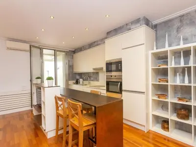 a kitchen with white cabinets and a wooden table and chairs at Apartment Centro- Passeig de Gracia - Casa Batllo by Interhome in Barcelona