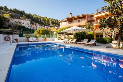 a swimming pool with chairs and an umbrella next to a building at Hotel Robert in La Pobla de Claramunt