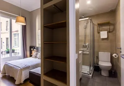a bathroom with a shower and a toilet and a bed at El Born Guest House by Casa Consell in Barcelona