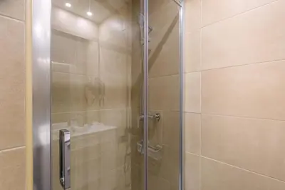 a shower with a glass door next to a sink at El Born Guest House by Casa Consell in Barcelona