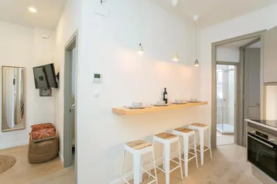 a kitchen with white walls and bar stools at Canela Homes BARCELONA MARINA in Barcelona