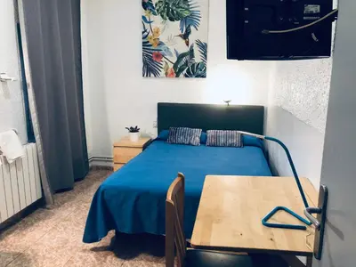 a bedroom with a blue bed and a wooden table at Hostal Carlos III in El Prat de Llobregat