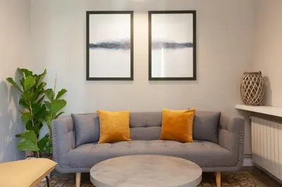 a living room with a blue couch with orange pillows at My Address on the Beach and Sun in Barcelona