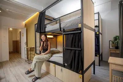a woman talking on a cell phone in a room with bunk beds at Onefam Paralelo in Barcelona