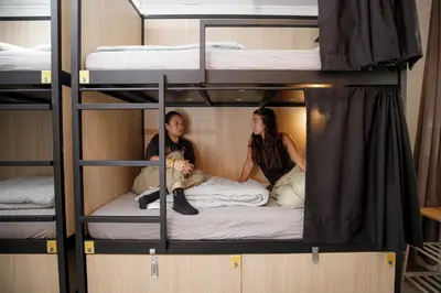 two women sitting on a bunk bed in a room at Onefam Paralelo in Barcelona