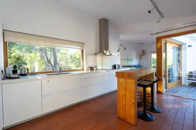 a kitchen with white cabinets and a large window at Villa Can Tomeu Capdet in Sant Pere de Ribes