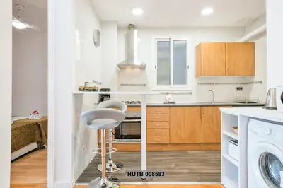 a kitchen with white cabinets and a chair in it at Alcam Berlin-Numancia in Barcelona