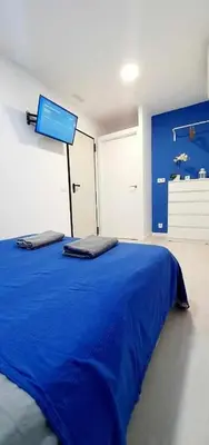 a bedroom with a blue bed with a tv on the wall at Hostal Urban Basic in Hospitalet de Llobregat