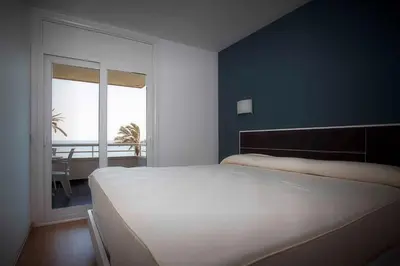 a bedroom with a large white bed and a window at Apartamentos Sunway Talaia in Sitges