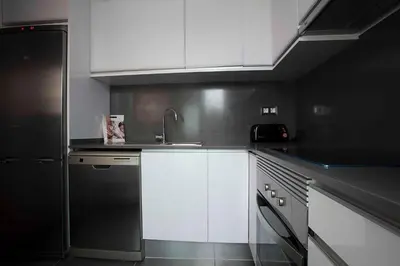 a kitchen with white cabinets and a black refrigerator at Apartamentos Sunway Talaia in Sitges