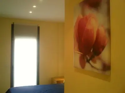 a bedroom with a painting of a flower on the wall at Apartamentos Sitges in Sitges